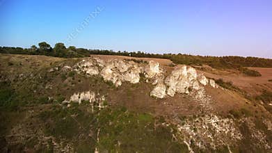 Drone closing up on a mountainside, rocky hill with the cliff.