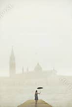 Woman with umbrella walks on a pier to admire the city