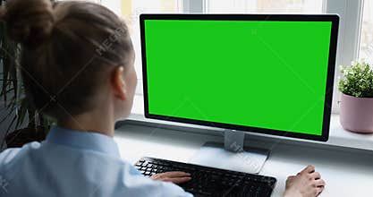 Woman using desktop computer in office, scrolling mouse. mockup with blank green screen