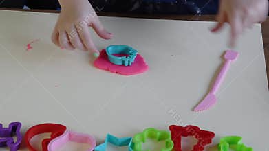 Hands of little girl 3-5 years old playing pink play dough with plastic molds