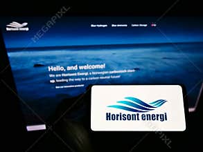 Person holding smartphone with logo of Norwegian carbontech company Horisont Energi AS on screen in front of website.
