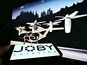 Person holding smartphone with logo of startup and aerospace company Joby Aviation (air taxi) on screen.