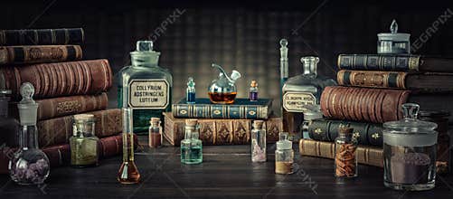 Glass bottles, old books on table of a scientist. Medicine, chemistry, pharmacy, apothecary, alchemy history background.
