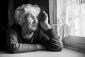 An elderly woman in her house. Black and white photo.