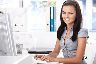 Pretty secretary typing on computer smiling