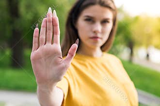 Close up of the hand of a beautiful and young Caucasian girl showing Stop Sign.