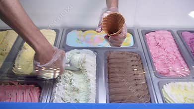 Close-up of a showcase with different flavors of Italian ice cream. The seller takes a delicious cold dessert with a