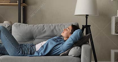 Relaxed serene happy young woman sleeping on cozy sofa.