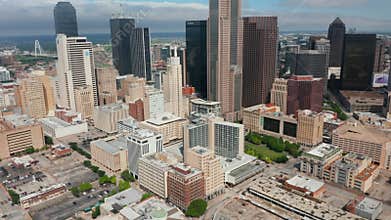 Tilt up reveal of modern downtown skyscrapers. Forwards fly above streets of city. Dallas, Texas, US.