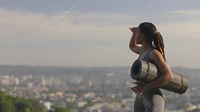 Fitness black woman holding yoga mat and water bottle