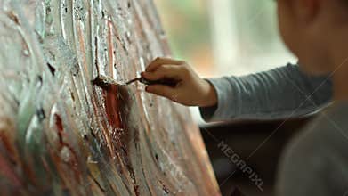 Young painter drawing on canvas. Child hand holding painting tool in art studio.