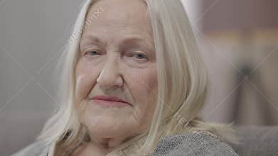 Headshot portrait of sad lonely old Caucasian woman with grey hair looking at camera with upset facial expression