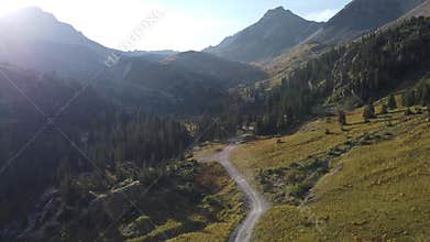 Aerial over gravel road with jeep driving through large valley in the Colorado mountains