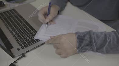 Highlighting a book during the study near a laptop