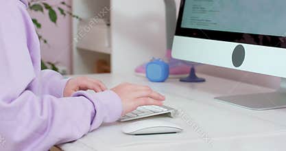 Close up hands of teen girl typing on keybord and scrolling mouse, working with computer,