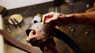 A man paints edges of a blank for a leather belt
