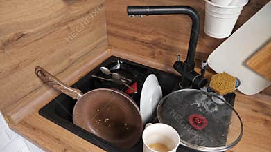 Heap of dirty dishes after cooking breakfast lies in sink