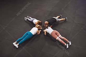 Fit people planking together on the floor of a gym