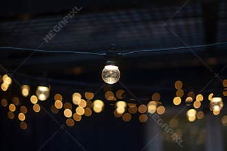 Electric lamp garlands with different size bulbs hanging in a cafe, attached to the ceiling. Evening party or wedding decorations