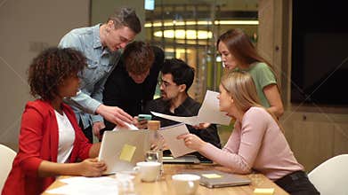 Front view of stressed overworked ceo chief sitting at table with laptop reading paper document, male and female