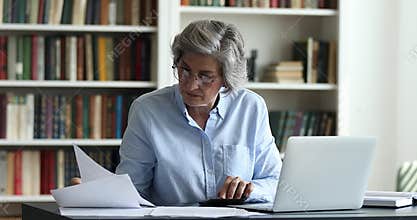 Focused 50s accountant manages company accounting working in office