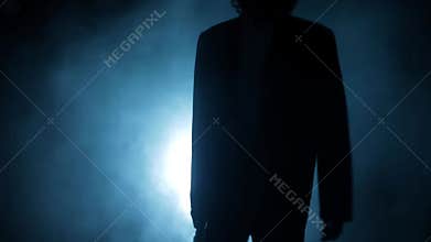 Cinematic slow motion shot of a gangster mafia man walking with a gun in his hand. Dramatic shot of a man in dark lighting with so