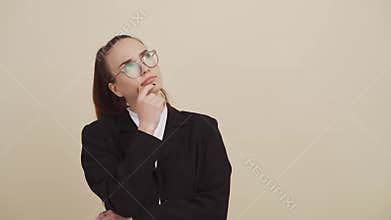 Young woman on beige background thinking about something