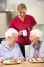 Carer drinking tea with two elderly woman