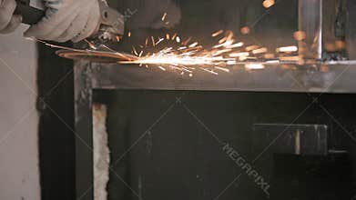 manual cleaning of welded seams with an angle grinder with a flap disc on welded metal construction close-up with long