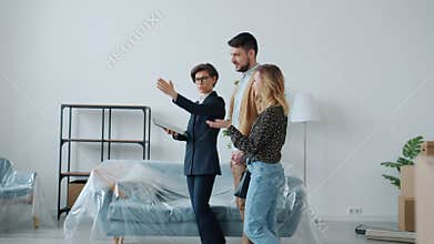 Real estate broker using tablet and showing new house to buyers man and woman talking gesturing