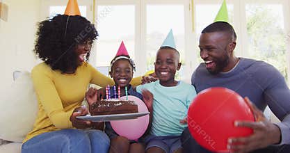 African american boy blowing candles on the cake and celebrating birthday with family at home