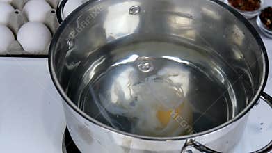 Recipe for cooking poached eggs. Raw egg is placed in boiling water in saucepan, after stirring water with spoon. And