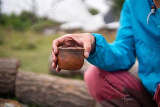 Drinking Chinese tea Pu Erh outdoor Near the Campfire Oven in Ecovillage. Clay tea pot, cup and pot on the little wooden