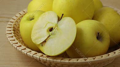 Whole and halved  fresh yellow apples in a basket