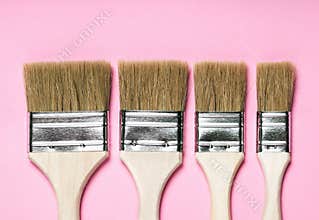 Flat paintbrushes on pink background