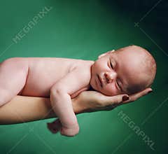 New born baby resting on mom's hand.