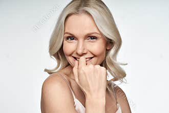 Happy middle aged blonde woman looking at camera advertising face skin care.