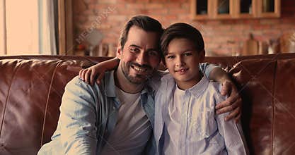 Happy young affectionate dad cuddling little son.