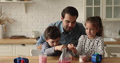Father and kids play with science kits making chemical experiments