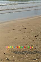 Happy birthday colorful candles on beach