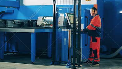 Factory worker operating metal forming machine