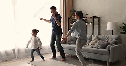 Happy emotional parents dancing with cute daughter at home.