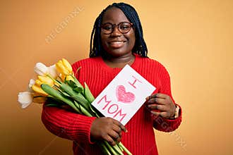 Plus size african american woman holding love mom message and tulips on mothers day with a happy face standing and smiling with a