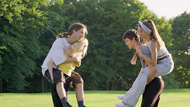 Group of teenagers 16, 17 years old are having fun together in summer in park on green lawn