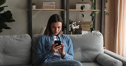 Carefree happy young 20s woman using cellphone at home.