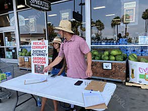 Workers at a table collect petition signatures for a California recall election attempt against Los Angeles County District Attorn