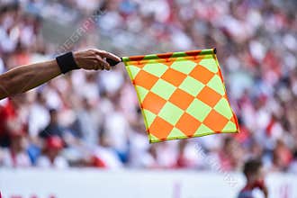 Hand of assistant of football referee with raised flag