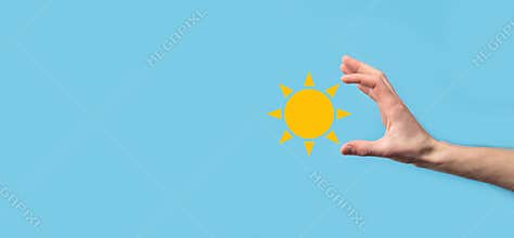 Hand on blue background holds sun icon symbol.Sustainable source of electricity, power supply concept. Eco environmentally