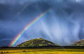 Storm rain shower cloud colourful bright vibrant rainbow over rural landscape Great Britain United Kingdom