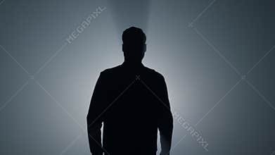 Silhouette man walking in darkness. Male person going straight on in dark.